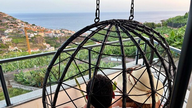 A person sitting in a spherical hanging chair with a view of a coastal town and the sea. - GuestReady - Seaview Escape (Câmara de Lobos)