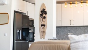 A modern kitchen with white cabinets, a stainless steel refrigerator, and a microwave. - GuestReady - Seaview Escape (Câmara de Lobos)