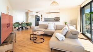 A modern living room with a sofa, coffee table, and dining area. - GuestReady - Seaview Escape (Câmara de Lobos)