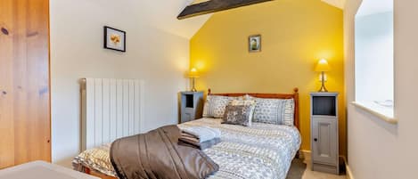 A bedroom with a bed, bedside tables, a radiator, and a window.