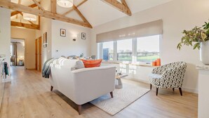 A spacious living room with a sofa, a patterned armchair, and a dining area with a table and chairs. - 1 Bed in Market Weston (oc-t27890) (Market Weston)