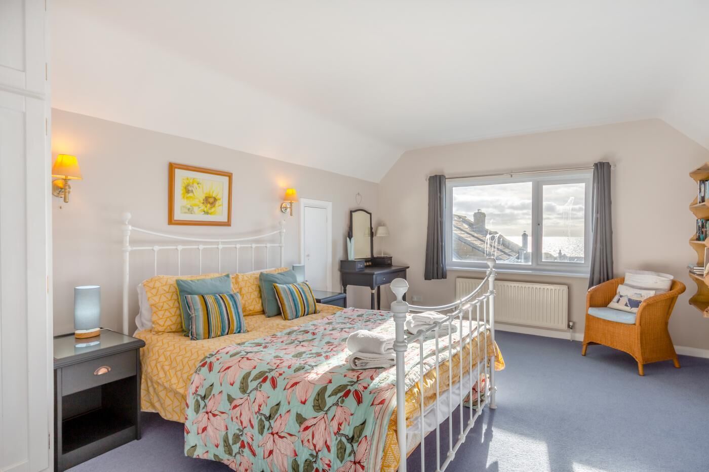 A bedroom with a bed, bedside tables, a chair, a window with a view, and a radiator.