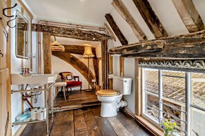 A rustic bathroom with exposed wooden beams, a white toilet, a wooden chair, a mirror, and a window with a view. - 3 Bed in Rumburgh (oc-c27094) (Rumburgh)