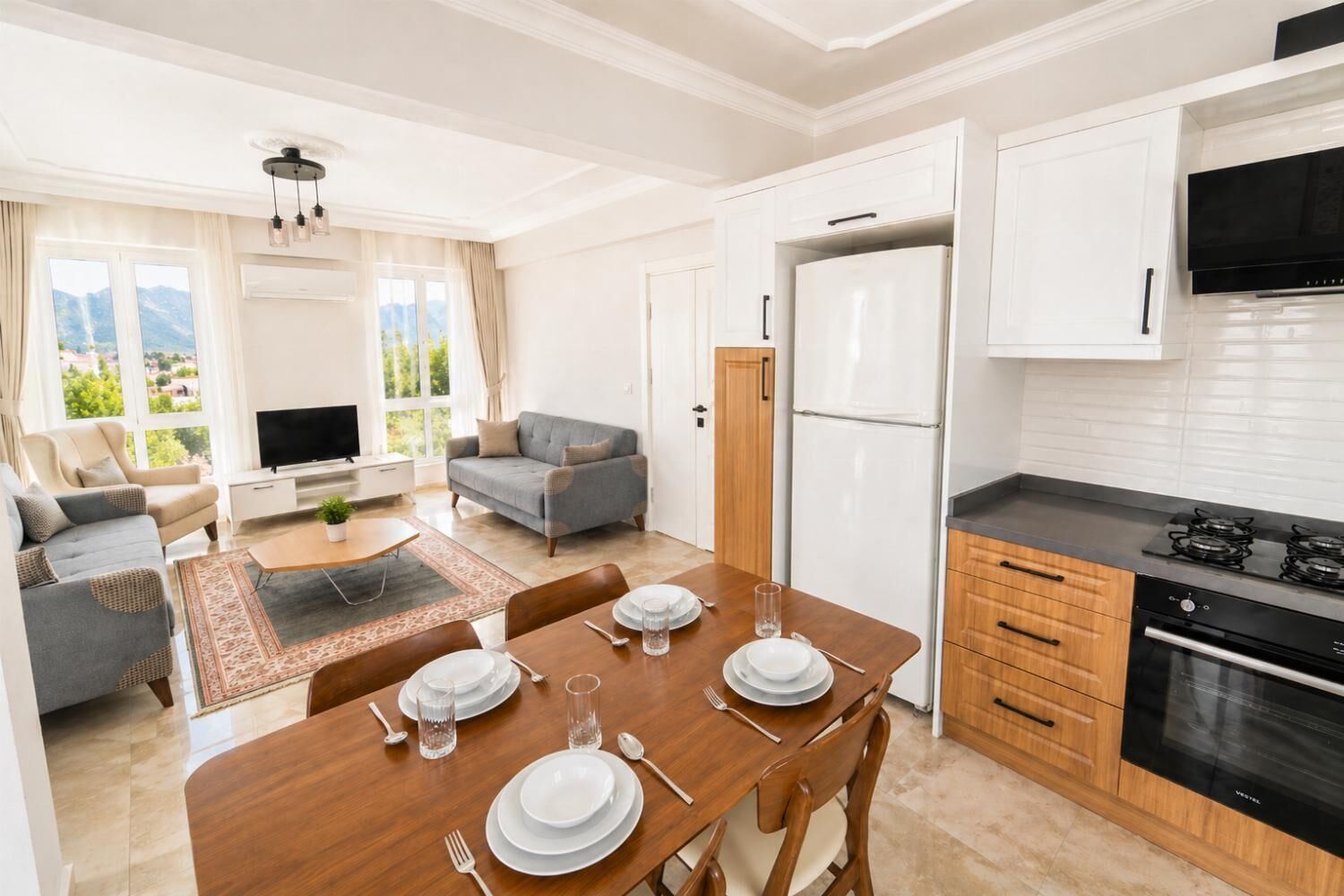 Un apartamento moderno con comedor, cocina, sala de estar y un amplio ventanal con vista a la montaña.