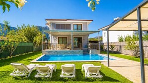 A two-story house with a swimming pool, outdoor seating, and a covered patio.