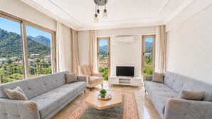 A spacious living room with two grey sofas, a wooden coffee table, and a TV stand.