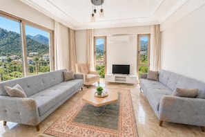 A spacious living room with two grey sofas, a wooden coffee table, and a TV stand.