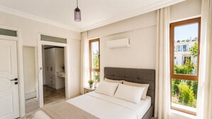 A bedroom with a bed, a wardrobe, a bathroom, and a window with a view.