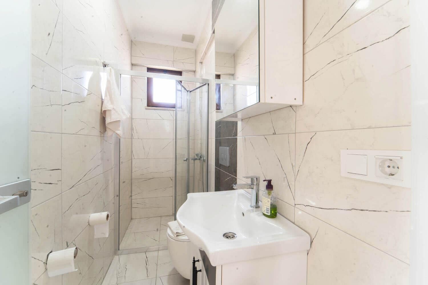Un baño con ducha, inodoro, lavamanos y espejo.
