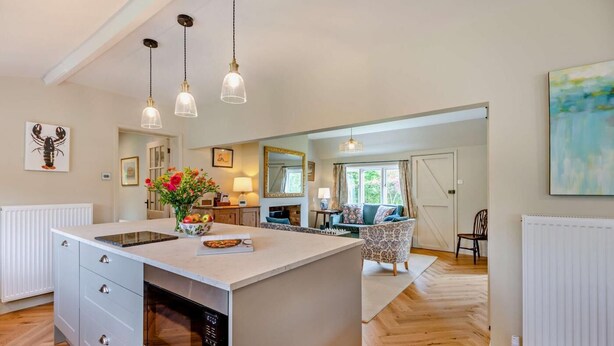A spacious kitchen with a large island, pendant lights, and a view to a living area. - 3 Bed in Marden (oc-w28286) (Horsmonden)