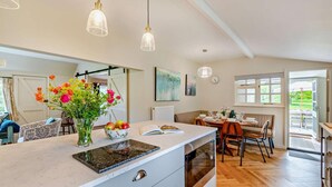 A modern kitchen with a central island, wooden flooring, and pendant lighting. - 3 Bed in Marden (oc-w28286) (Horsmonden)