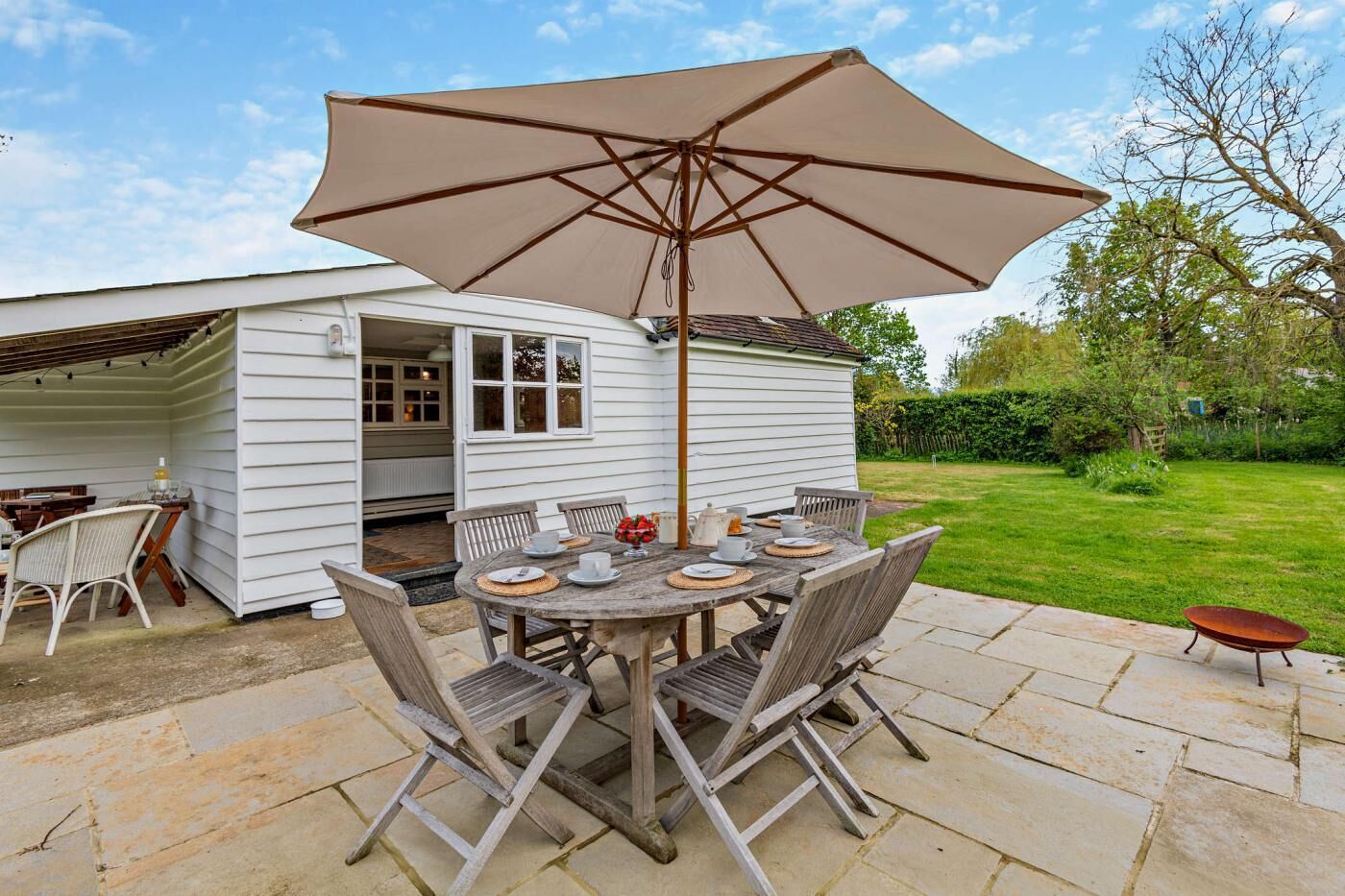 An outdoor patio with a round table, chairs, and a large umbrella.