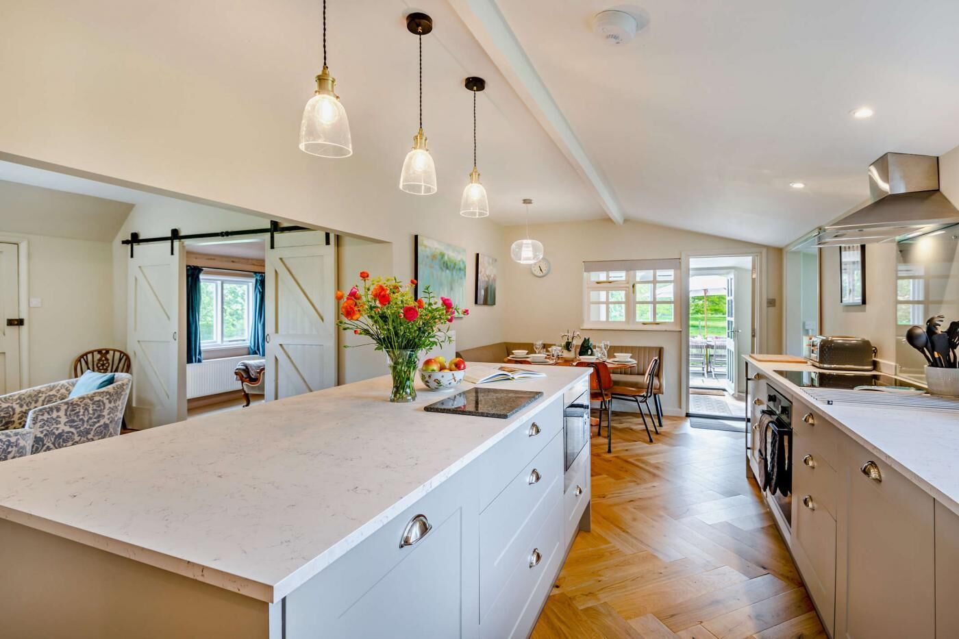 A spacious kitchen with a large island, pendant lighting, and a view to the outdoors.