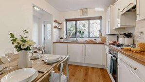 A modern kitchen with white cabinets, a wooden countertop, and a dining area with a table set for two. - 2 Bed in Charlestown (oc-91449) (Charlestown)