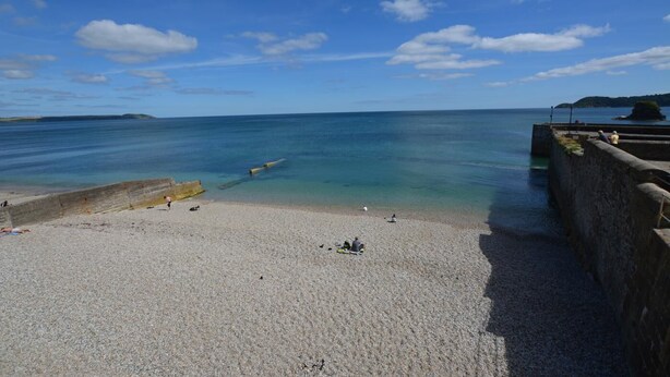 A pebble beach with clear water, a distant island, and a stone wall on the right. - 2 Bed in Charlestown (oc-91449) (Charlestown)