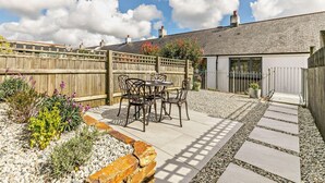 A patio area with a table and chairs, surrounded by a wooden fence and gravel paths. - 2 Bed in Charlestown (oc-91449) (Charlestown)