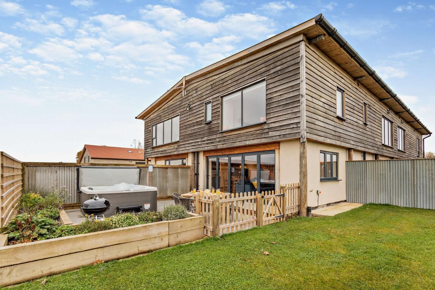 Een tweelaags huis met een patio, een hottub en een omheinde achtertuin.
