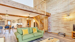 A spacious living area with a green sofa, wooden coffee table, and a staircase leading to an upper level. - 2 Bed in Outwell (oc-a28259) (Upwell)