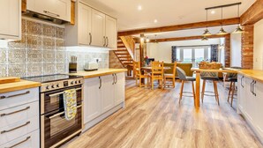 A modern kitchen with white cabinets, a wooden countertop, and a built-in oven. There is a dining area with wooden chairs and a table. - 2 Bed in Outwell (oc-a28259) (Upwell)
