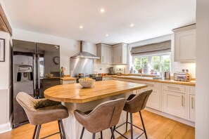 A modern kitchen with a central island, stainless steel appliances, and bar stools. - 4 Bed in East Rudham (oc-t28312) (East Rudham)
