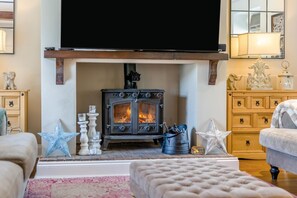 A cozy living room with a fireplace, a television mounted above it, and a comfortable seating area. - 4 Bed in East Rudham (oc-t28312) (East Rudham)