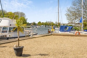 A marina with boats docked, a small palm tree, and a gravel walkway. - 3 Bed in Christchurch (oc-r27898) (Christchurch)
