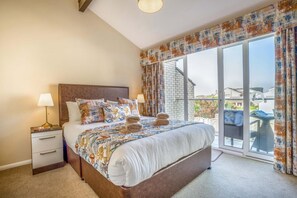 A bedroom with a large bed, a nightstand, a lamp, and a view of the outdoors. - 3 Bed in Christchurch (oc-r27898) (Christchurch)