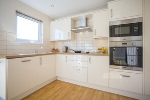 A modern kitchen with white cabinets, a stainless steel oven, and a window. - 3 Bed in Christchurch (oc-r27898) (Christchurch)