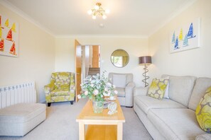 A living room with a sofa, armchair, coffee table, and a mirror on the wall. - 3 Bed in Christchurch (oc-r27897) (Christchurch)