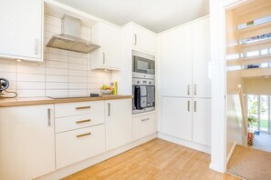 A modern kitchen with white cabinets, a microwave, and a stove. - 3 Bed in Christchurch (oc-r27897) (Christchurch)