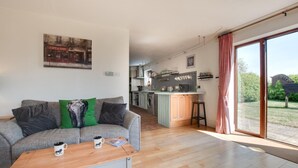 A modern living room with a grey sofa, a coffee table, and a kitchen in the background. - 2 Bed in Barnby (oc-t28265) (North Cove)