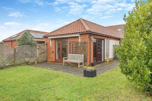 A brick house with a tiled roof, a wooden fence, a bench, and a small garden. - 2 Bed in Barnby (oc-t28265) (North Cove)