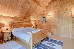 A wooden bedroom with a bed, bedside tables, a nightstand, a wall-mounted lamp, and a door. - 3 Bed in Little Petherick (oc-c28311) (Little Petherick)