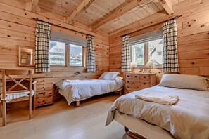 A wooden cabin bedroom with two beds, a desk, and a dresser. - 3 Bed in Little Petherick (oc-c28311) (Little Petherick)