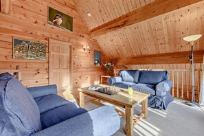 A cozy wooden interior with a sofa, a table with chess, and a lamp. - 3 Bed in Little Petherick (oc-c28311) (Little Petherick)