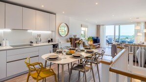 Une cuisine moderne avec des meubles blancs, un coin repas doté d’une table ronde et un balcon offrant une vue agréable.