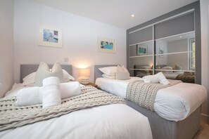Ein modernes Schlafzimmer mit zwei Betten, einem großen Spiegel und Bildern an den Wänden.