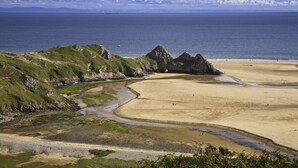 A coastal landscape with a sandy beach, rocky outcrops, and a clear view of the sea. - 2 Bed in Southgate (oc-p28298) (Southgate)