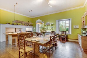 Une cuisine spacieuse avec un coin repas, des meubles en bois et des luminaires suspendus.