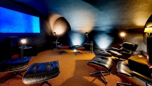 Een bioscoopzaal met een groot scherm, meerdere zithoeken en een projecteur.