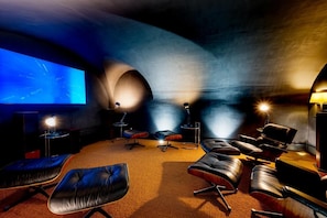 Une salle de cinéma dotée d’un grand écran, de plusieurs espaces pour s’asseoir et d’un projecteur.