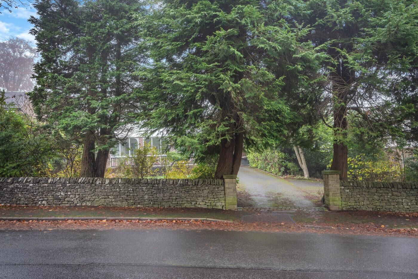 A stone wall with a paved path leading to a building.