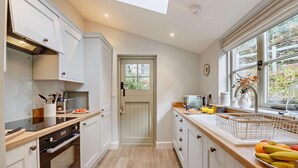 A modern kitchen with white cabinetry, a built-in oven, a coffee maker, and a fruit basket on the counter. - 2 Bed in Maentwrog (oc-g28262) (Maentwrog)