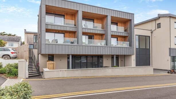 A modern multi-story building with a flat roof, large windows, and a wooden facade. - 2 Bed in Harlyn Bay (oc-a28321) (Harlyn Bay)
