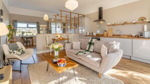 Ein modernes Wohnzimmer mit Sofa, Couchtisch und einem Essbereich mit Tisch und Stühlen.