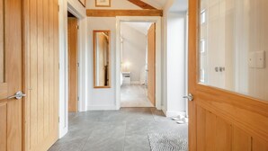 A hallway with wooden doors, a mirror, and a rug leading to a bedroom with a bed and nightstand. - 2 Bed in Chalbury (oc-t28279) (Horton)