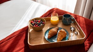 Ein Frühstücksbrett mit Croissants, einer Schüssel mit Beeren, einem Glas Orangensaft und einer Tasse.