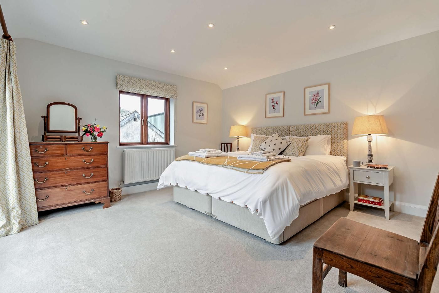 A bedroom with a bed, dresser, bedside tables, and a window.