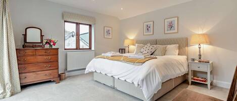 A bedroom with a bed, dresser, bedside tables, and a window.