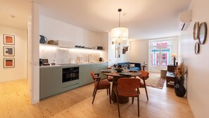 Una cocina moderna con zona de comedor, que incluye una isla central, iluminación colgante y vista a la calle.